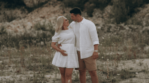 Pregnant Couple on Beach Embracing and looking into each others eyes