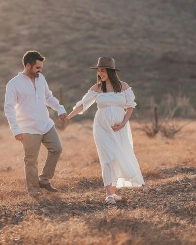 Expectant parents walking hand in hand on country