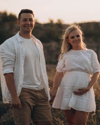 Pregnant mother and birth partner dressed in white in nature